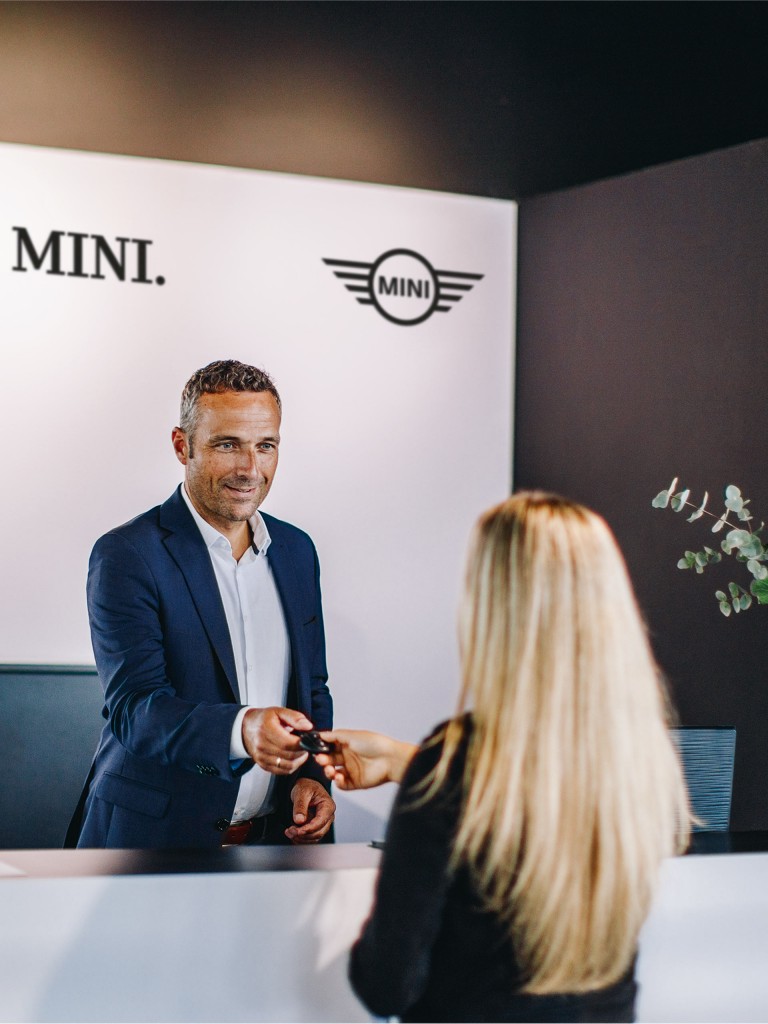 MINI SERVICE representative handing over car keys to a blond woman in one of the MINI SERVICE Centers